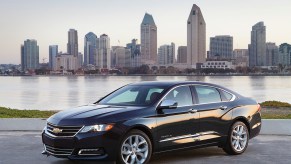 A black 2018 Chevy Impala parked in front of water and a cityscape