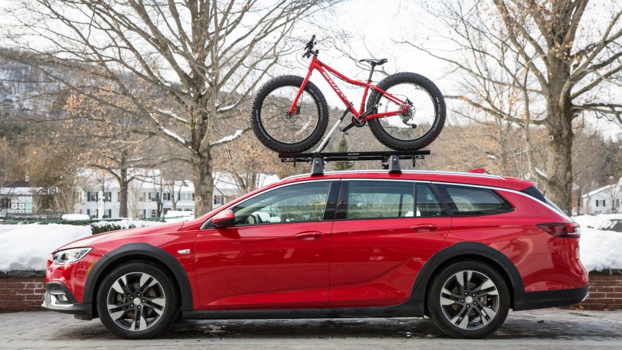 A red 2019 Buick Regal TourX carries a bicycle on its roof in Vermont during the winter