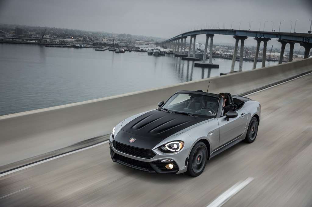A black and silver 2020 Fiat 124 Spider Abarth driving on a highway