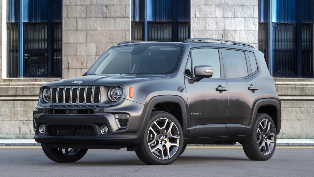 A dark-gray 2020 Jeep Renegade Limited is parked on a street outside a light-gray brick building