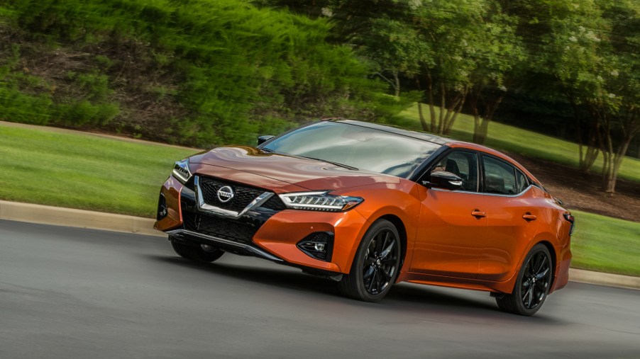An orange 2020 Nissan Maxima driving down a country road