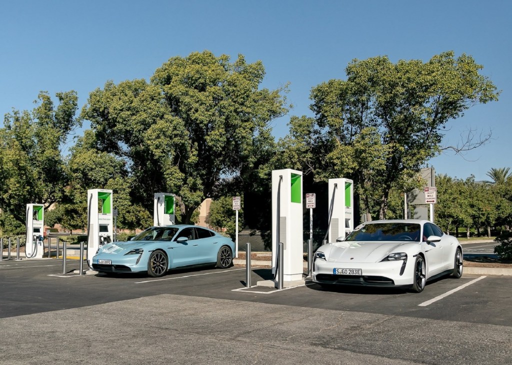 A light-blue and a white 2020 Porsche Taycan 4S at public chargers