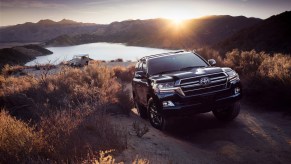 A 2020 Toyota Land Cruiser climbs a hill next to a lake.