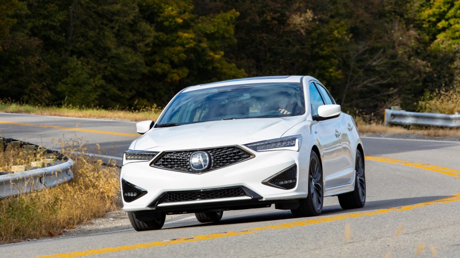 A white 2021 Acura ILX A-Spec drives on a winding country road