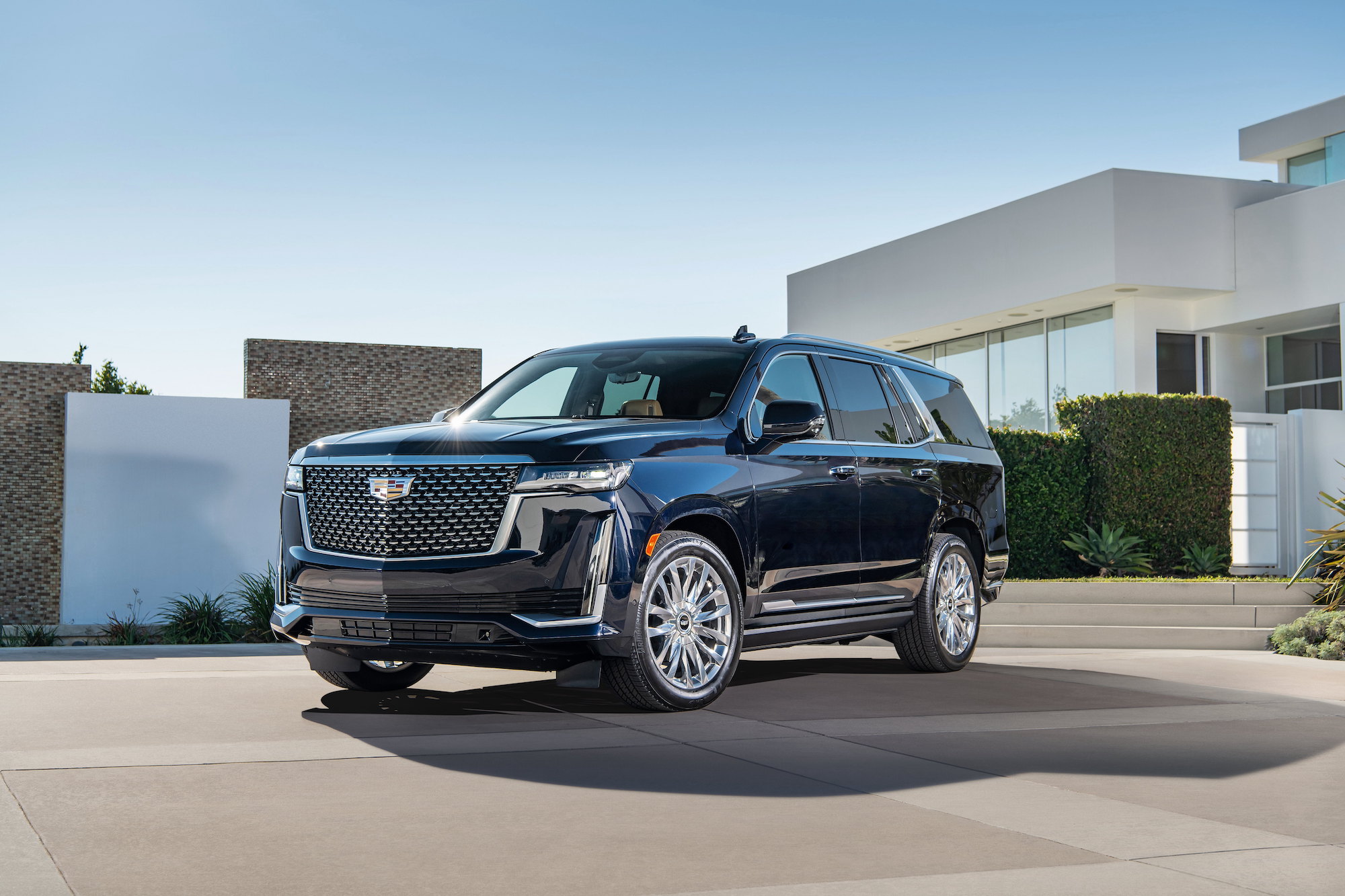 A black 2021 Cadillac Escalade is parked outside a modern home