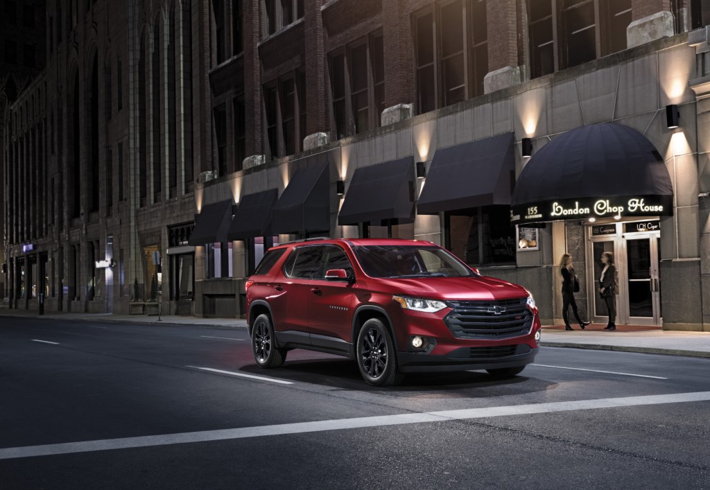 A red 2021 Chevy Traverse midsize SUV driving down a city street