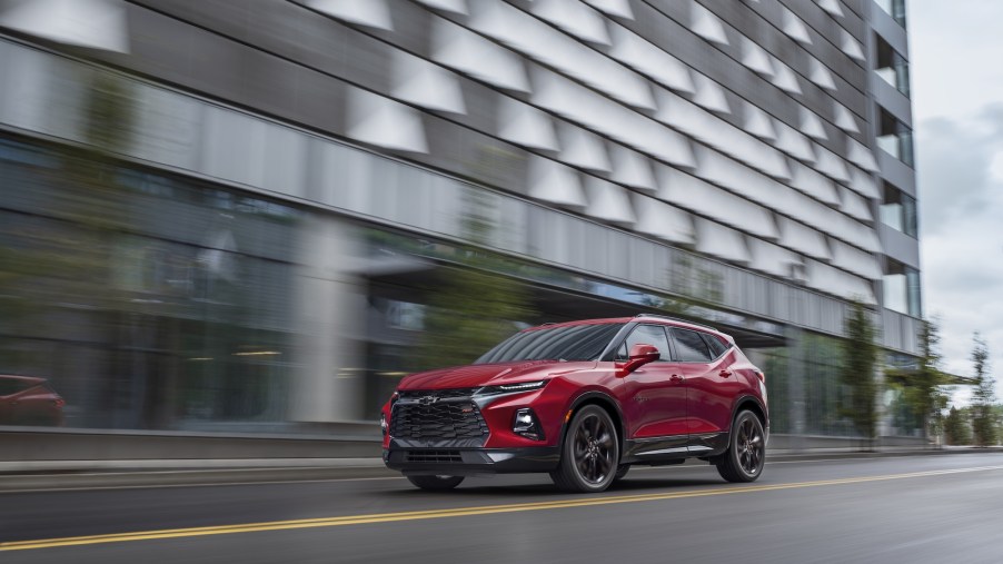 A red 2021 Chevy Blazer drives on a road past a large gray building