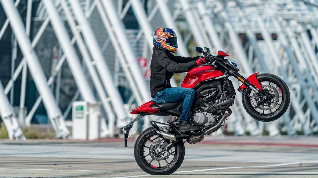 A rider wheelies a red 2021 Ducati Monster Plus