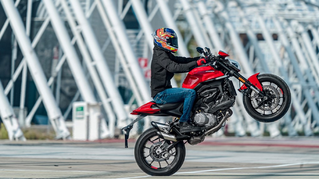 A rider wheelies a red 2021 Ducati Monster Plus