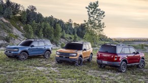 2021 Ford Bronco models in blue, yellow, and red sit on a hillside