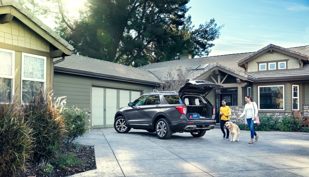 A family unloading the cargo area of a grey 2021 Ford Explorer in their driveway