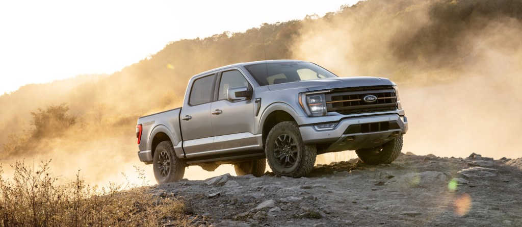 A silver 2021 Ford F-150 Tremor pickup truck stands atop a dusty hill
