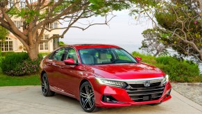 A red 2021 Honda Accord Hybrid parked in front of a house