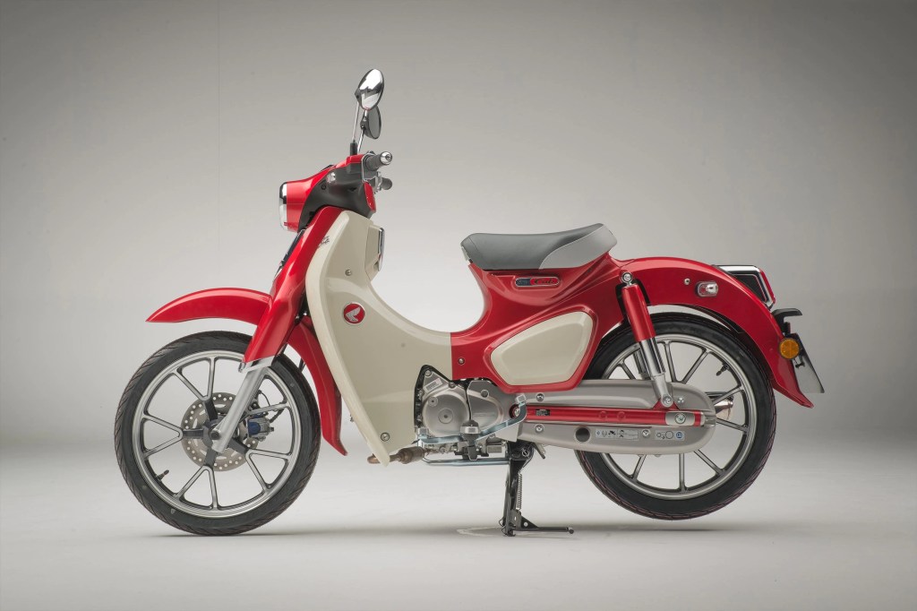 The side view of a red-and-white 2021 Honda Super Cub C125 ABS