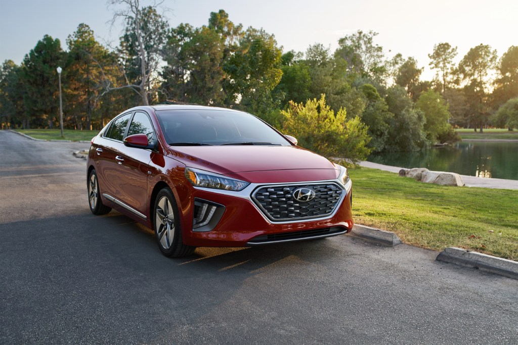 A red 2020 Hyundai Ioniq Hybrid parked on display with trees in the background