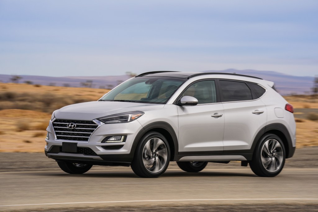 A silver 2021 Hyundai Tucson parked on display next to rugged terrain