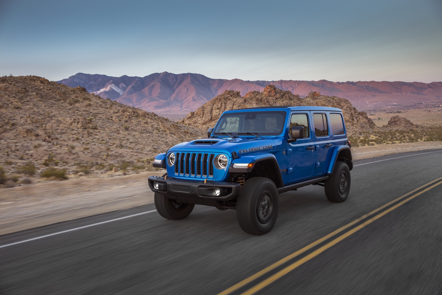 2021 Jeep Wrangler driving with a mountain range in the background
