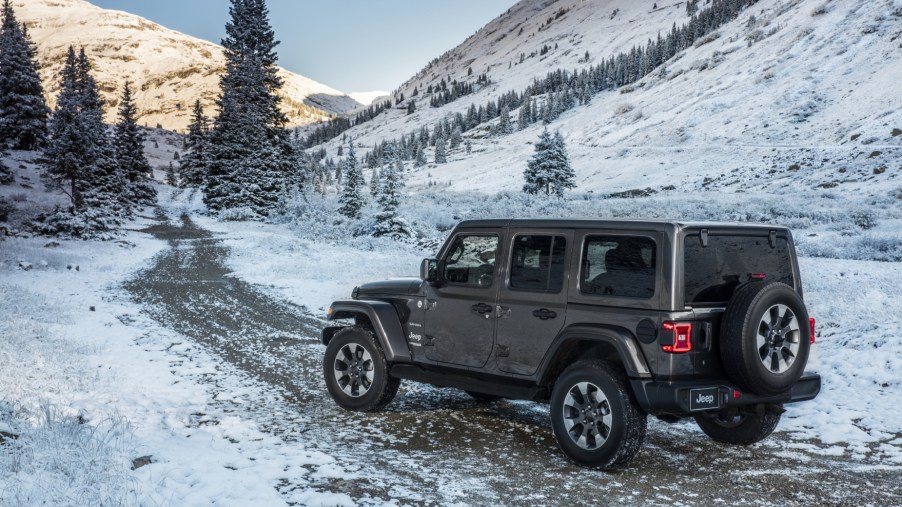 A grey 2021 Jeep Wrangler driving on a snowy road