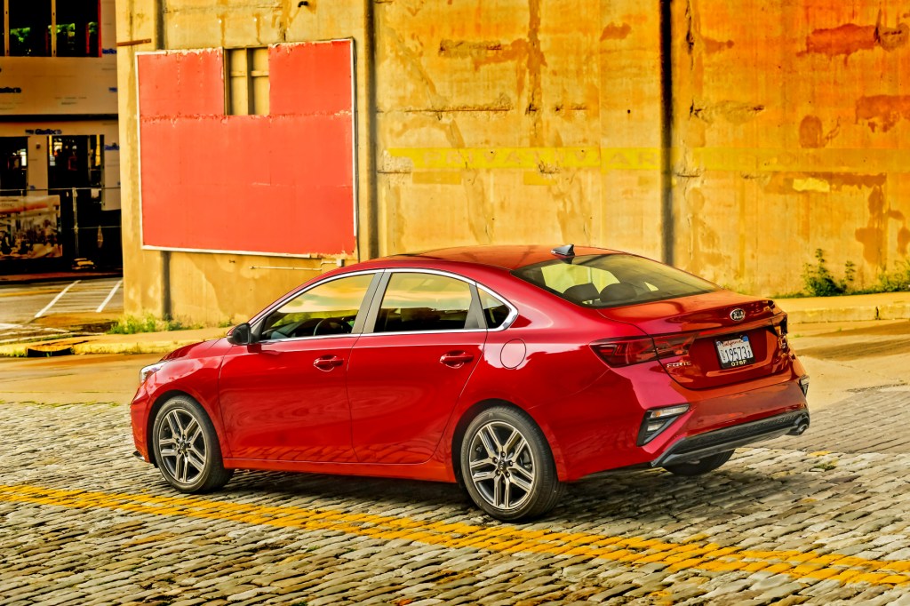 A red 2021 Kia Forte packed next to a colorful wall