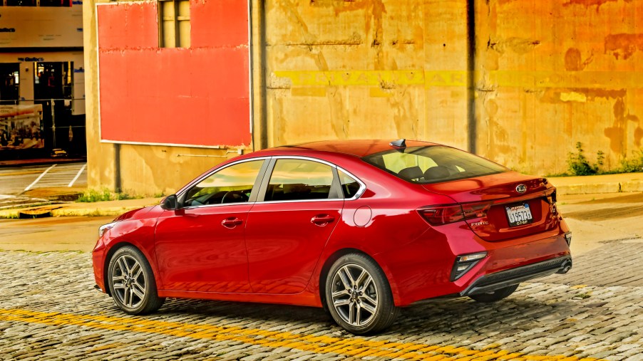 A red 2021 Kia Forte packed next to a colorful wall