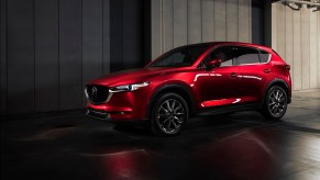 A metallic red 2021 Mazda CX-5 is parked next to a gray concrete building