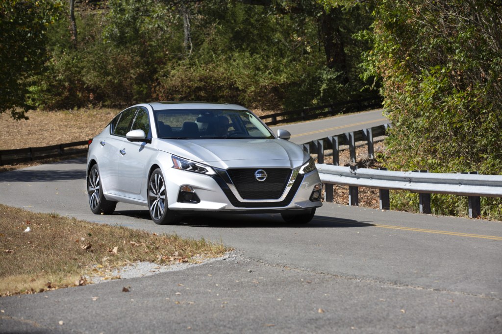 A silver 2021 Nissan Altima driving down a highway road exemplifies a top safety pick sedan