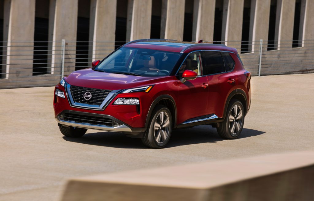 A red 2021 Nissan Rogue driving down a road