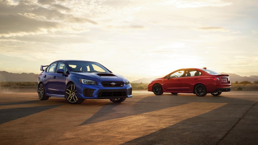 A blue 2021 Subaru WRX STI and a red 2021 Subaru WRX parked on display
