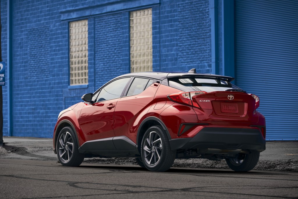 A red 2021 Toyota C-HR parked in front of a blue building