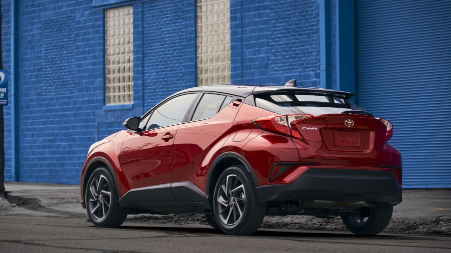 A red 2021 Toyota C-HR parked in front of a blue building