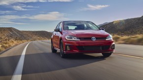 A red 2021 Volkswagen Golf GTI driving down a highway