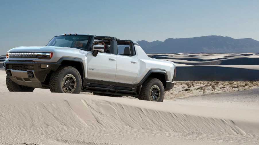 A white 2022 GMC Hummer EV truck drives dessert dunes
