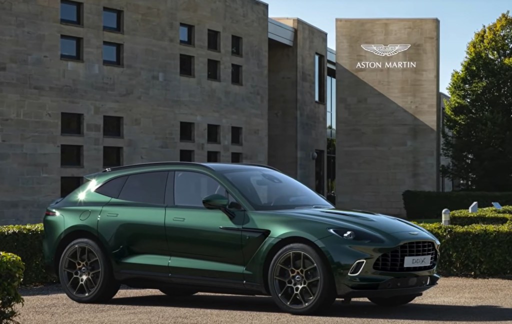 An Aston Martin DBX sits in front of a Aston Martin building