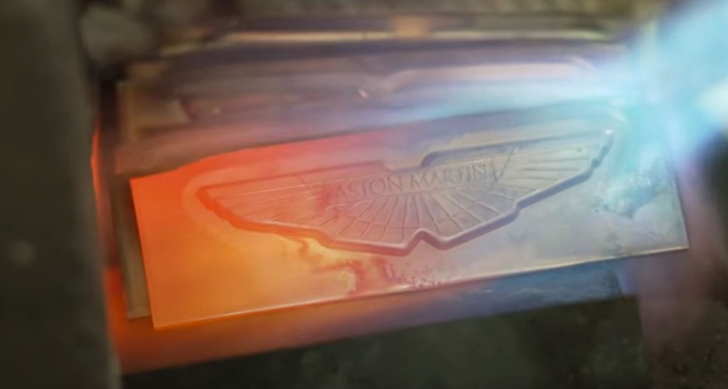 The Aston Martin wing badge undergoes heating from a torch.