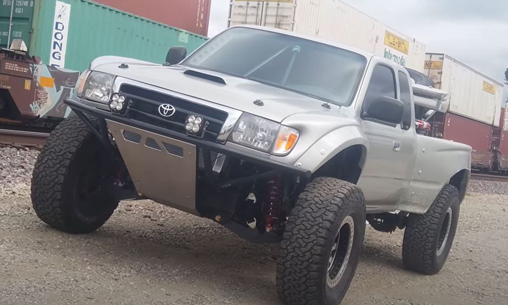 A silver lifted Toyota Tacoma with big tires.