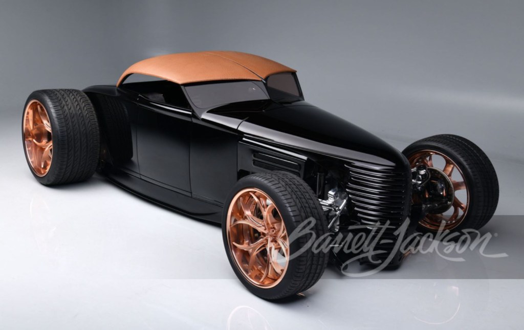The front quarter of a black custom rat rod sits on copper finished, one-off wheels.