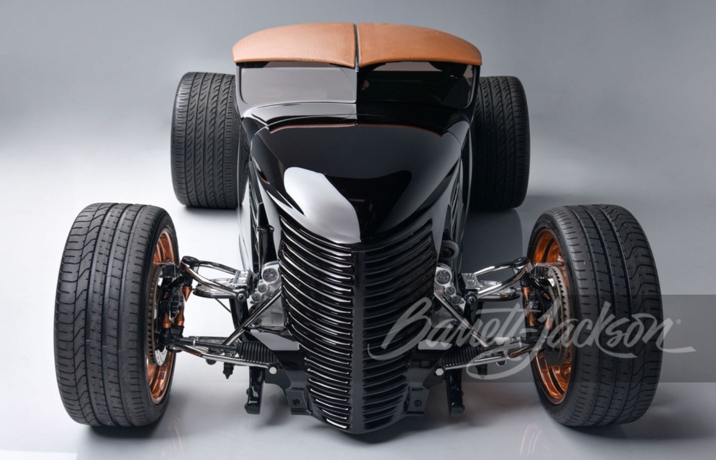 Head-on view of a black custom rat rod sits on copper finished, one-off wheels.
