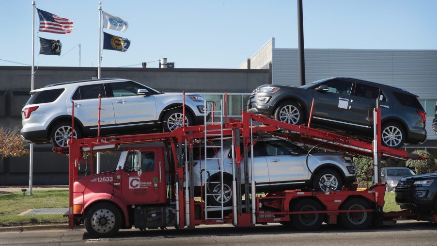 A truck carrying Ford SUVs to a car dealership