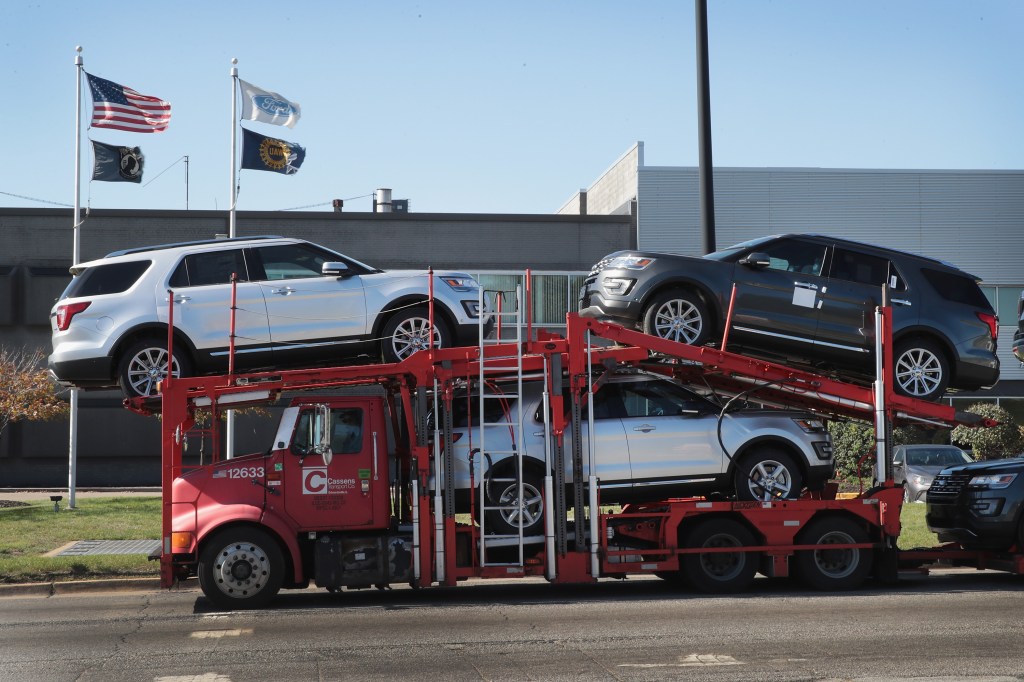 A truck carrying Ford SUVs to a car sales dealership
