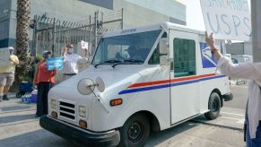 An image take just outside of a USPS dispatch center where trucks and workers are loading packages.