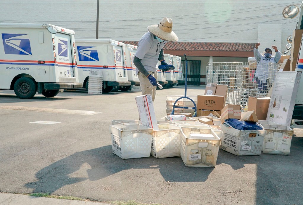 An image take just outside of a USPS dispatch center where trucks and workers are loading packages.