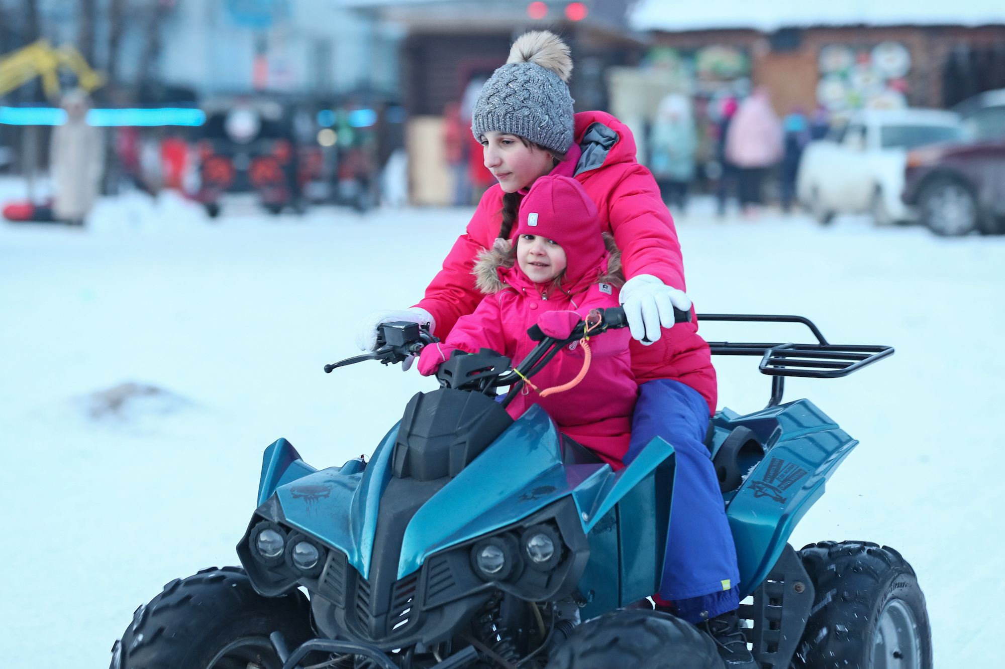 Two children driving an ATV at a ski resort