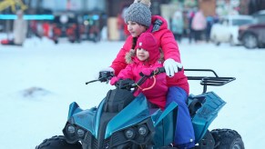 Two children driving an ATV at a ski resort