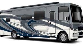 A white, gray, and blue Newmar Canyon Star diesel toy hauler RV.