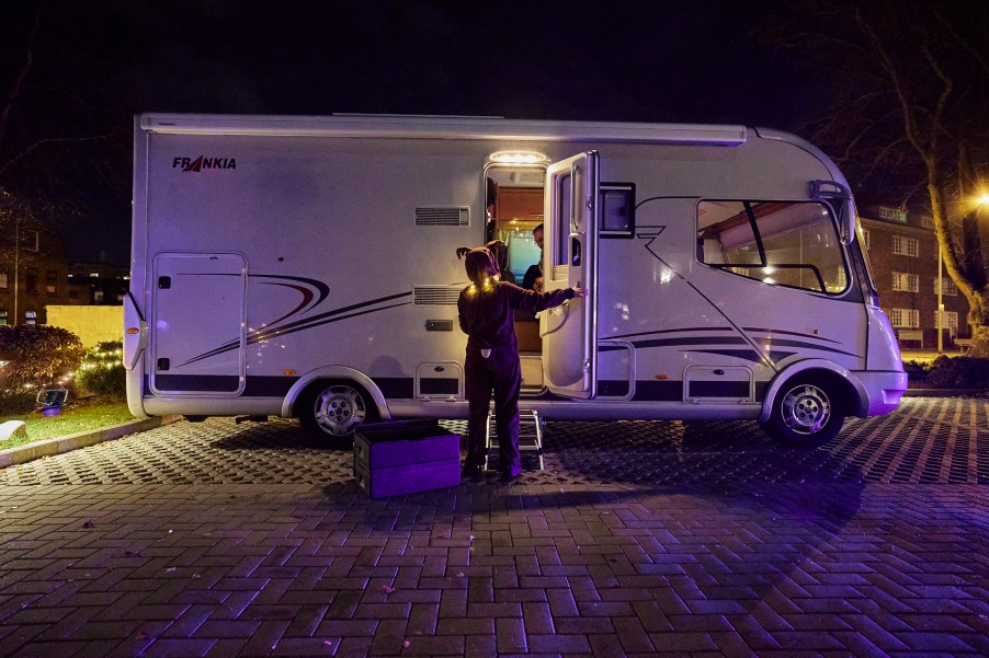 A costumed waitress serves the desert of a four-course dinner to a couple in their recreational vehicle (RV) in the parking lot of the Kochschule Neumuenster cooking school