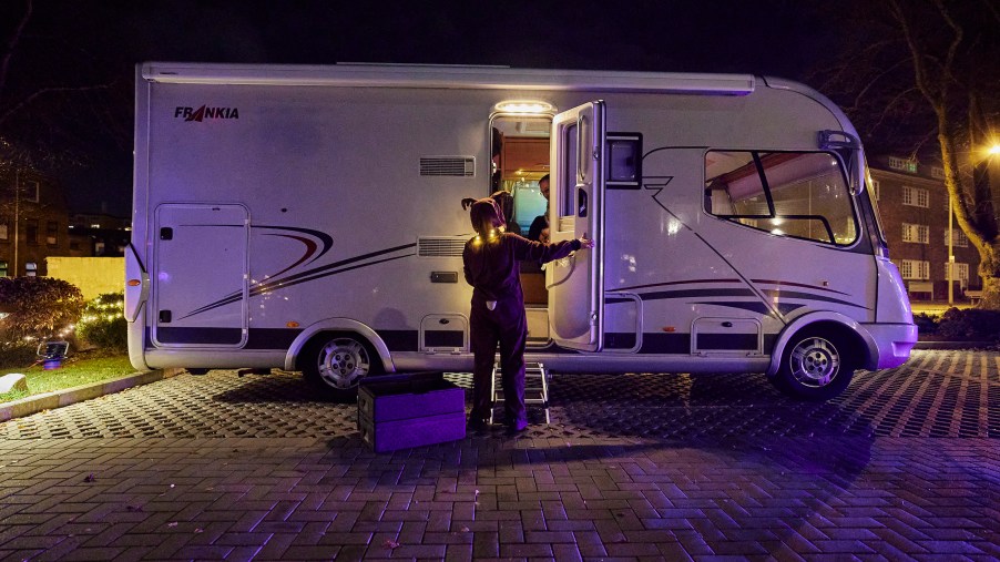 A costumed waitress serves the desert of a four-course dinner to a couple in their recreational vehicle (RV) in the parking lot of the Kochschule Neumuenster cooking school