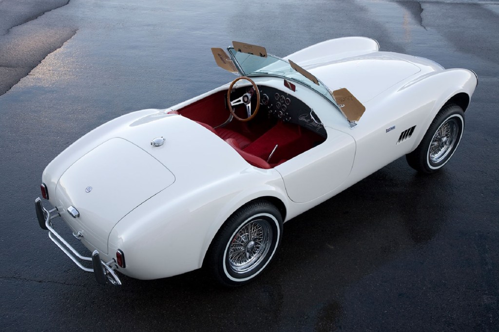 The overhead rear 3/4 view of a white Shelby Cobra 289 'Street Cobra' with a red interior