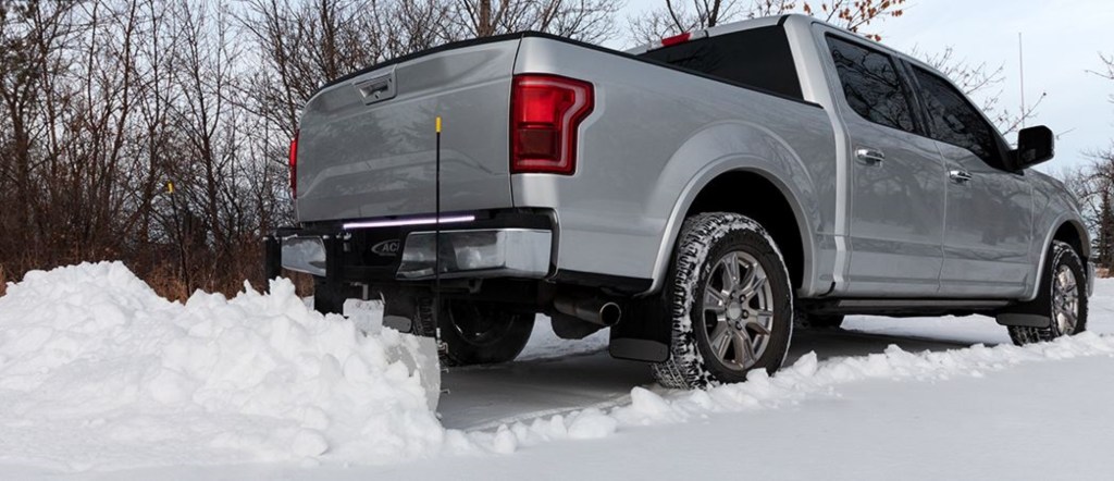 A rear hitch mounted snowplow is attached to a silver Ford F-150