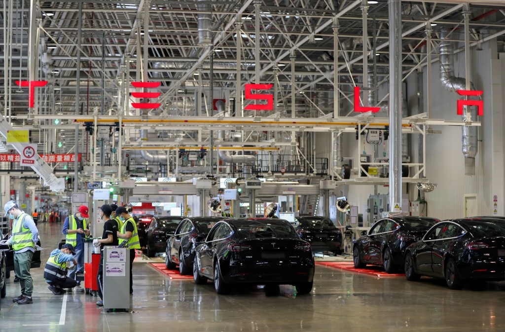 Employees working at a Tesla factory assembling cars
