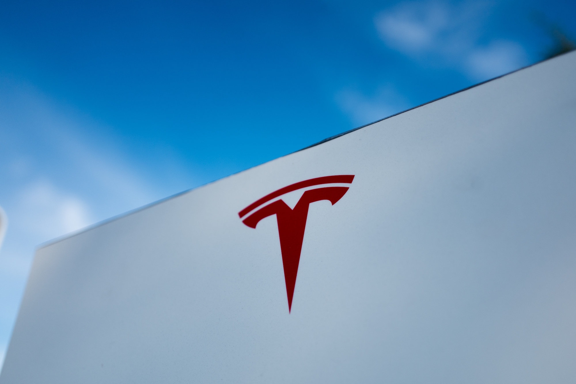 Close-up of Tesla Motors logo against a bright blue sky in Pleasanton, California, July 23, 2018.